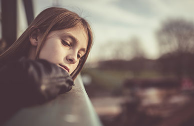 Depressed young girl looking out the window